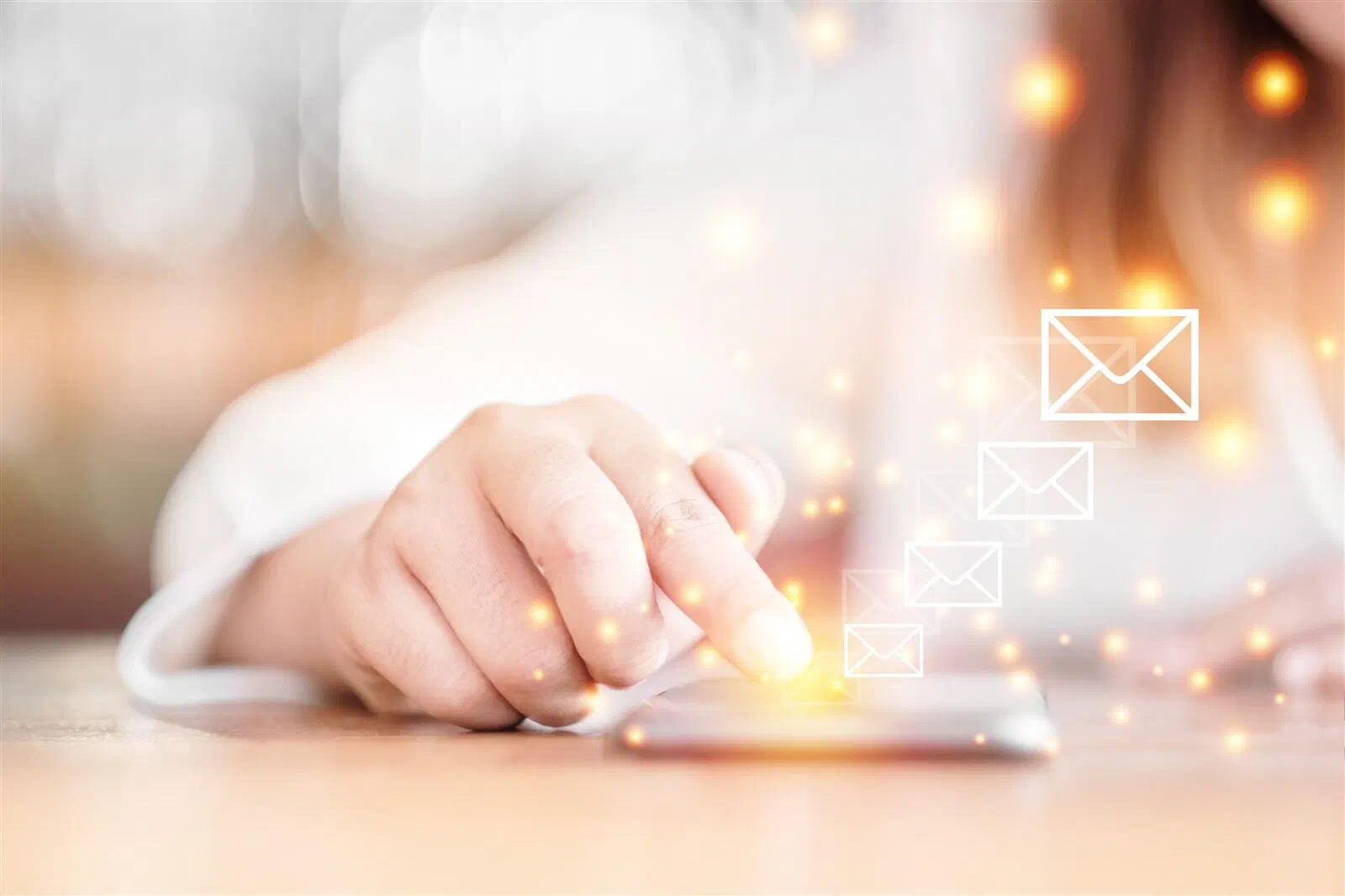A hand tapping a phone surrounded by glowing email envelope icons
