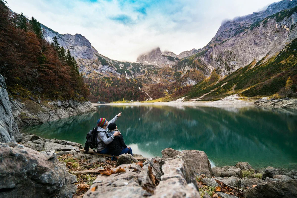 A couple sitting on a rock by a mountain lake